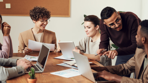 Adults meeting, using laptops and reviewing reports
